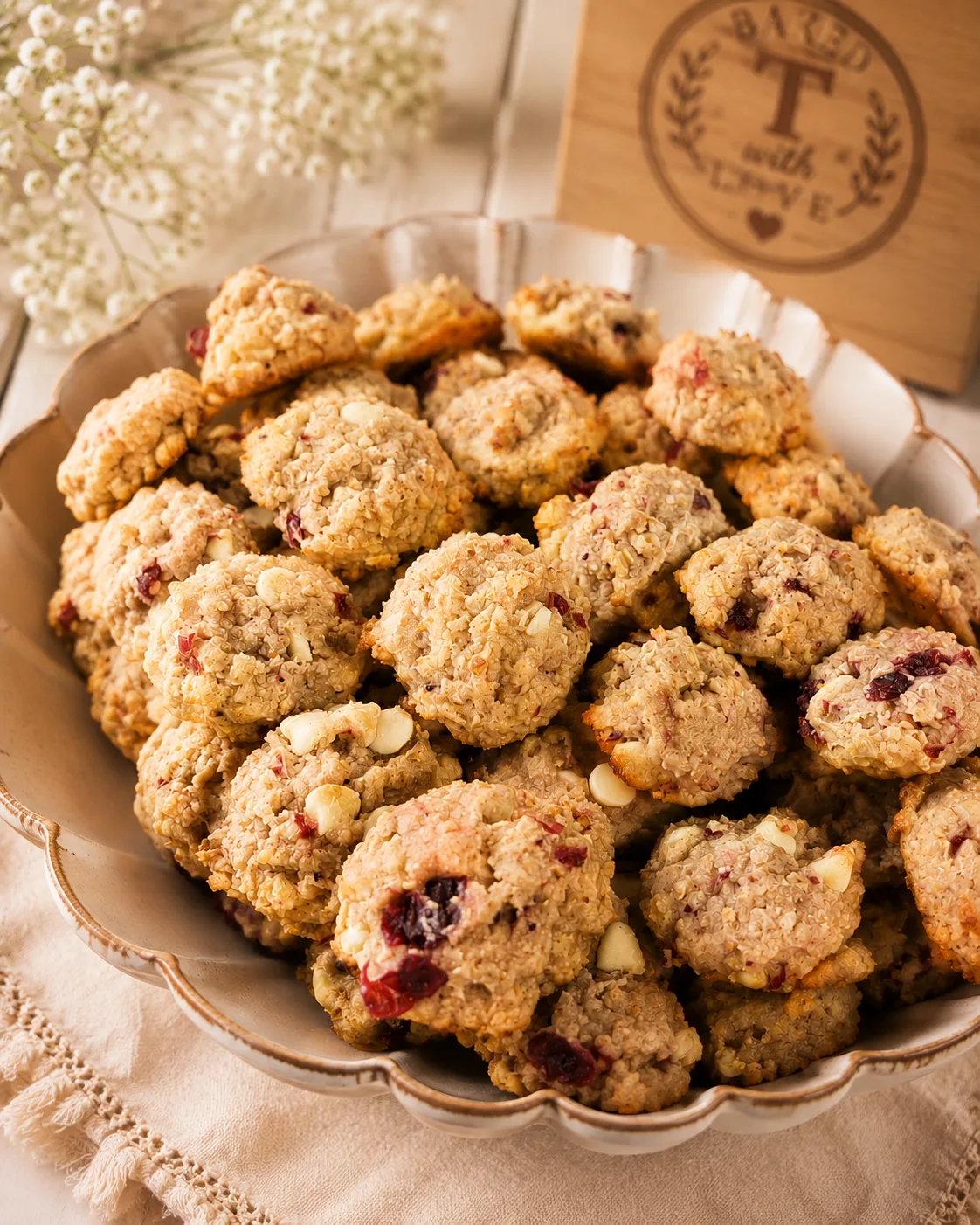 A shallow dish piled high with oat cookies studded with dried cranberries and white chocolate chunks.